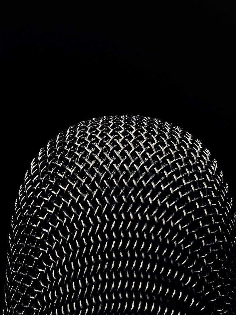 Close view of a microphone grille, the part that picks up both the voice and the room.